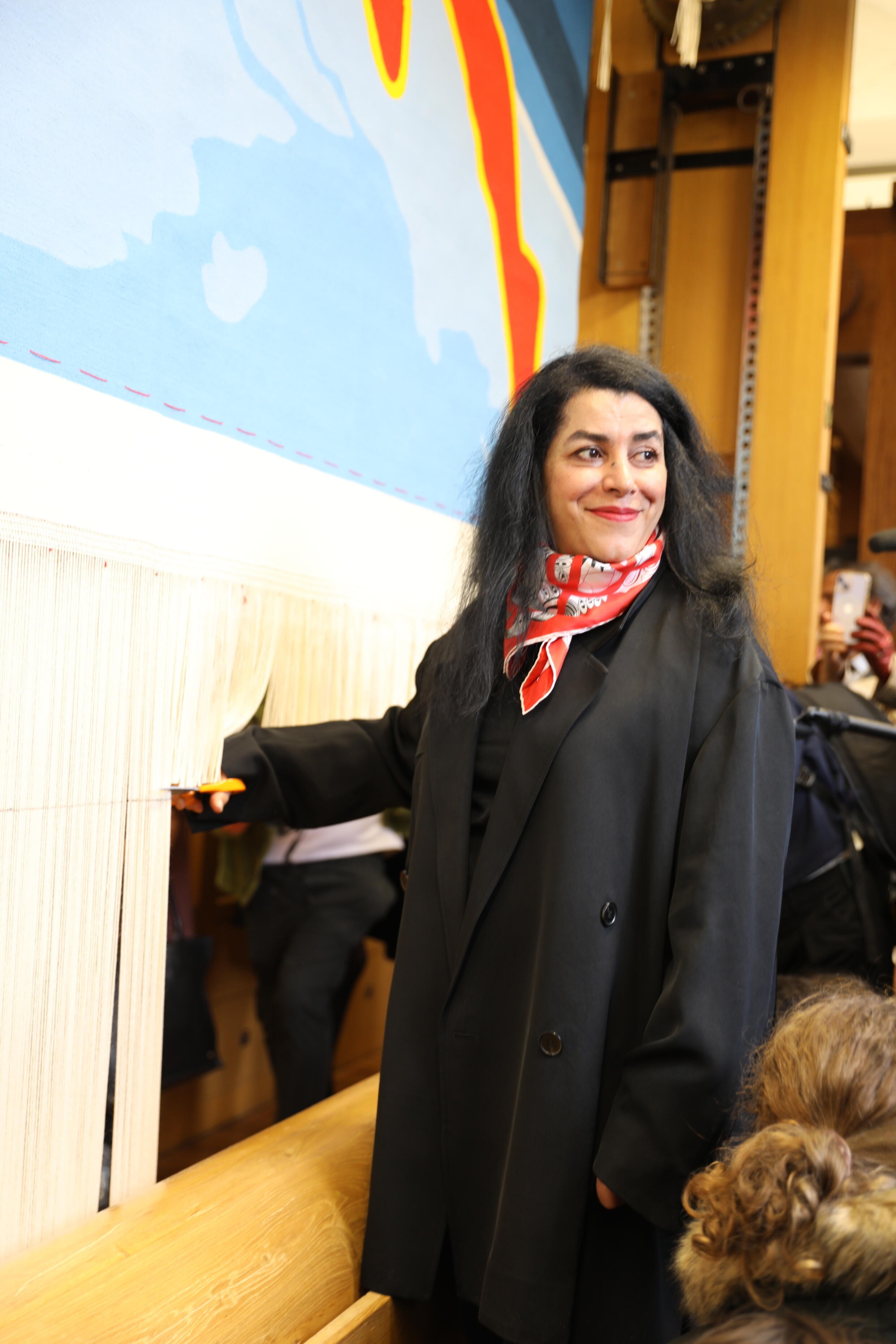L'artiste franco-iranienne Marjane Satrapi coupe le bord de la tapisserie des Jeux olympiques de Paris 2024 qu'elle a conçue. Elle a été dévoilée le 12 mars 2024 au Mobilier national à Paris.