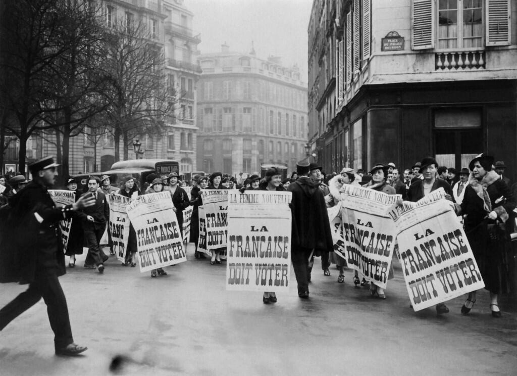 Des suffragettes françaises devant le Parlement à Paris en 1934, brandissant des pancartes indiquant : « Les Françaises doivent voter ».