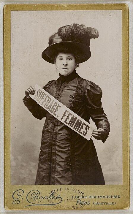 Portrait d'Hubertine Auclert avec une banderole appelant au suffrage des femmes, prise par Charles Gallot et conservée à la Bibliothèque Marguerite Durand à Paris.