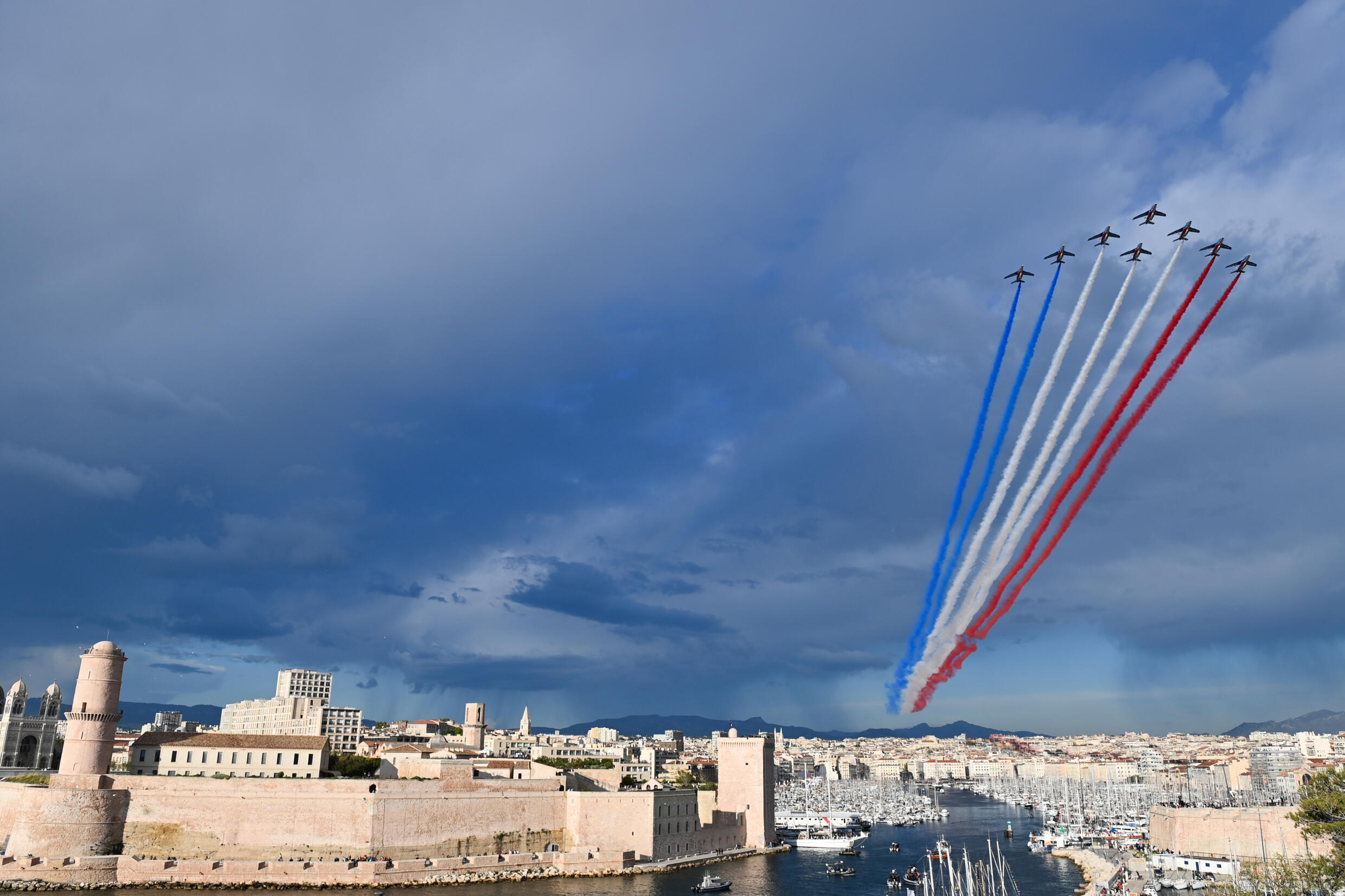 L'équipe de démonstration de l'Armée de l'Air pulvérise les couleurs du drapeau français au-dessus du Vieux-Port de Marseille à l'arrivée de la flamme olympique