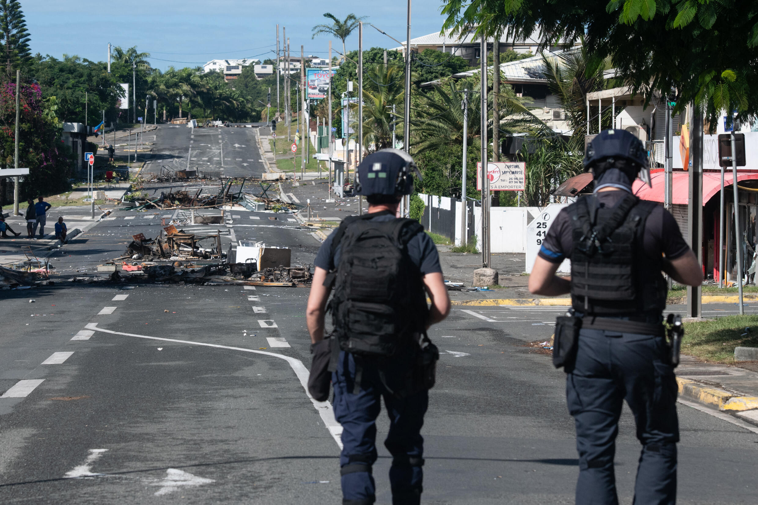 La police patrouille dans une rue bloquée par des débris et des objets incendiés à la suite de troubles nocturnes dans le quartier de Magenta à Nouméa, dans le territoire français du Pacifique de la Nouvelle-Calédonie, le 18 mai 2024.