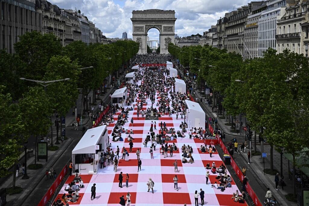 Des personnes participent à un pique-nique géant sur l'avenue des Champs-Elysées à Paris le 26 mai 2024.