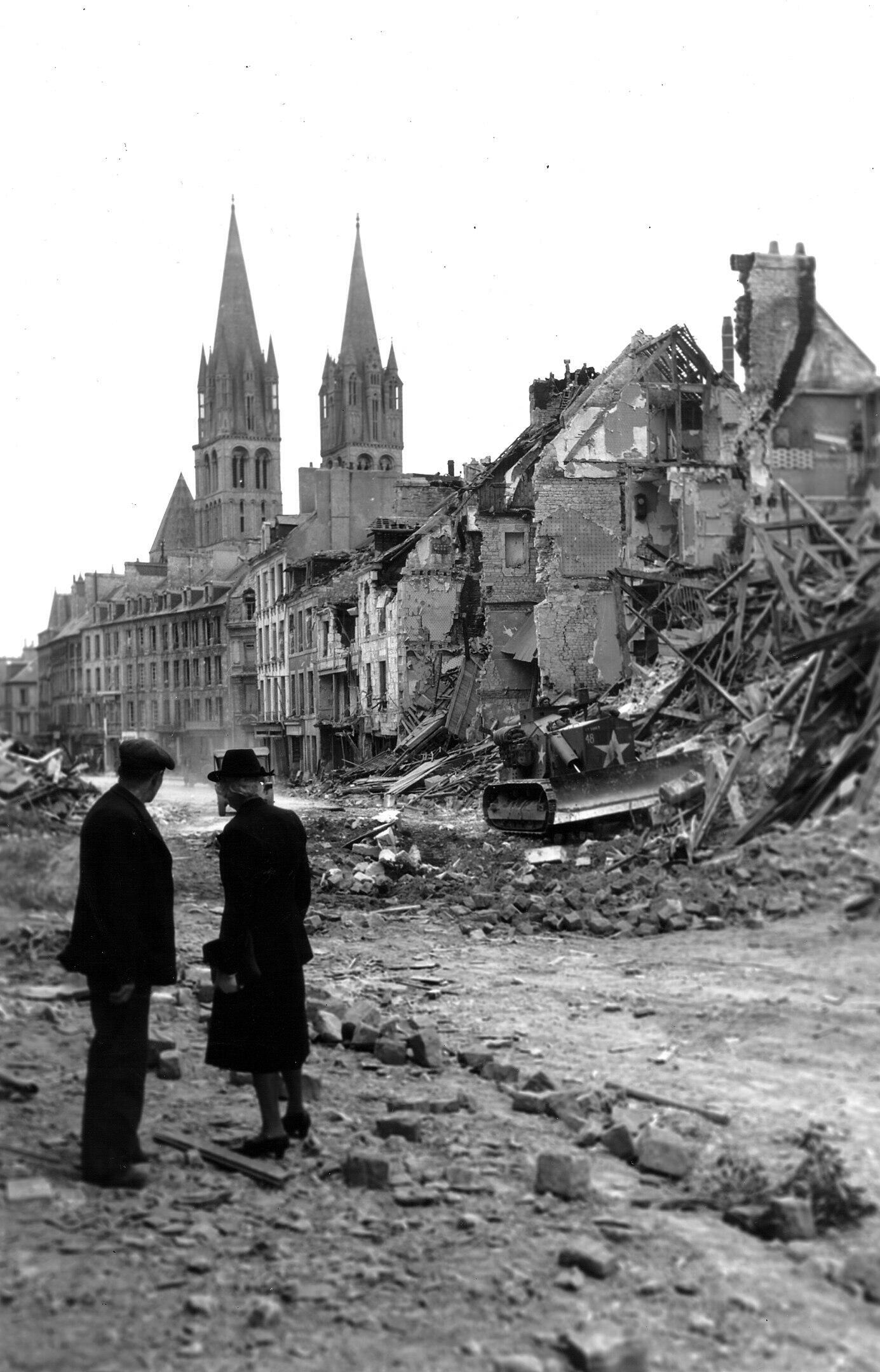Des habitants regardent un bulldozer dégager les ruines des maisons détruites à Caen, le 10 juillet 1944.