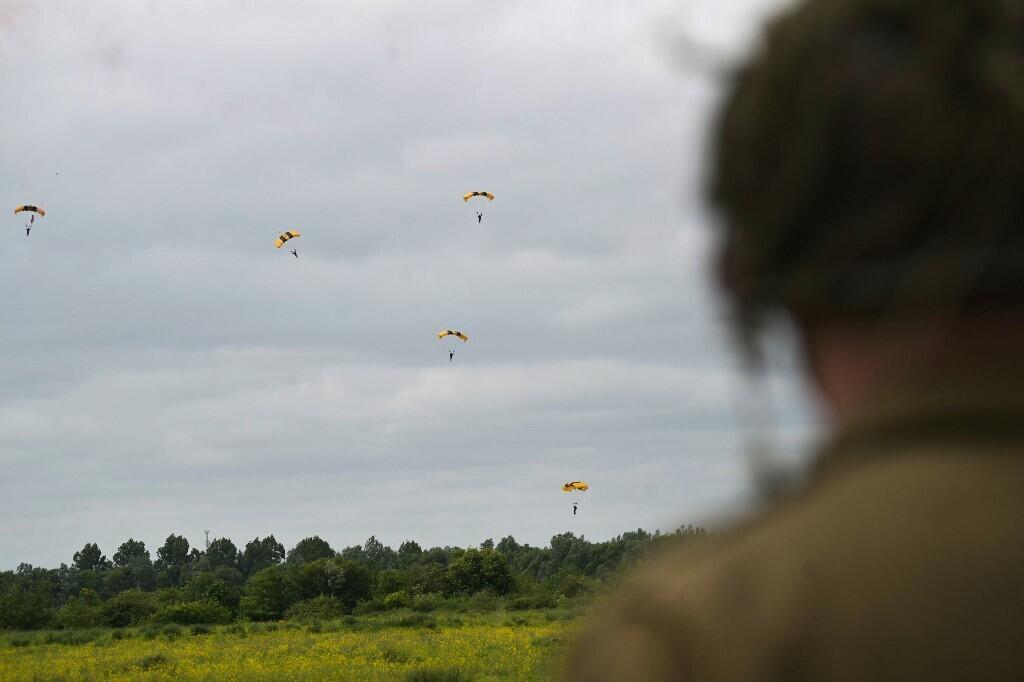 Des parachutistes américains atterrissent lors d'une reconstitution du jour J à Carentan-les-Marais, dans le nord-ouest de la France, le 2 juin 2024.
