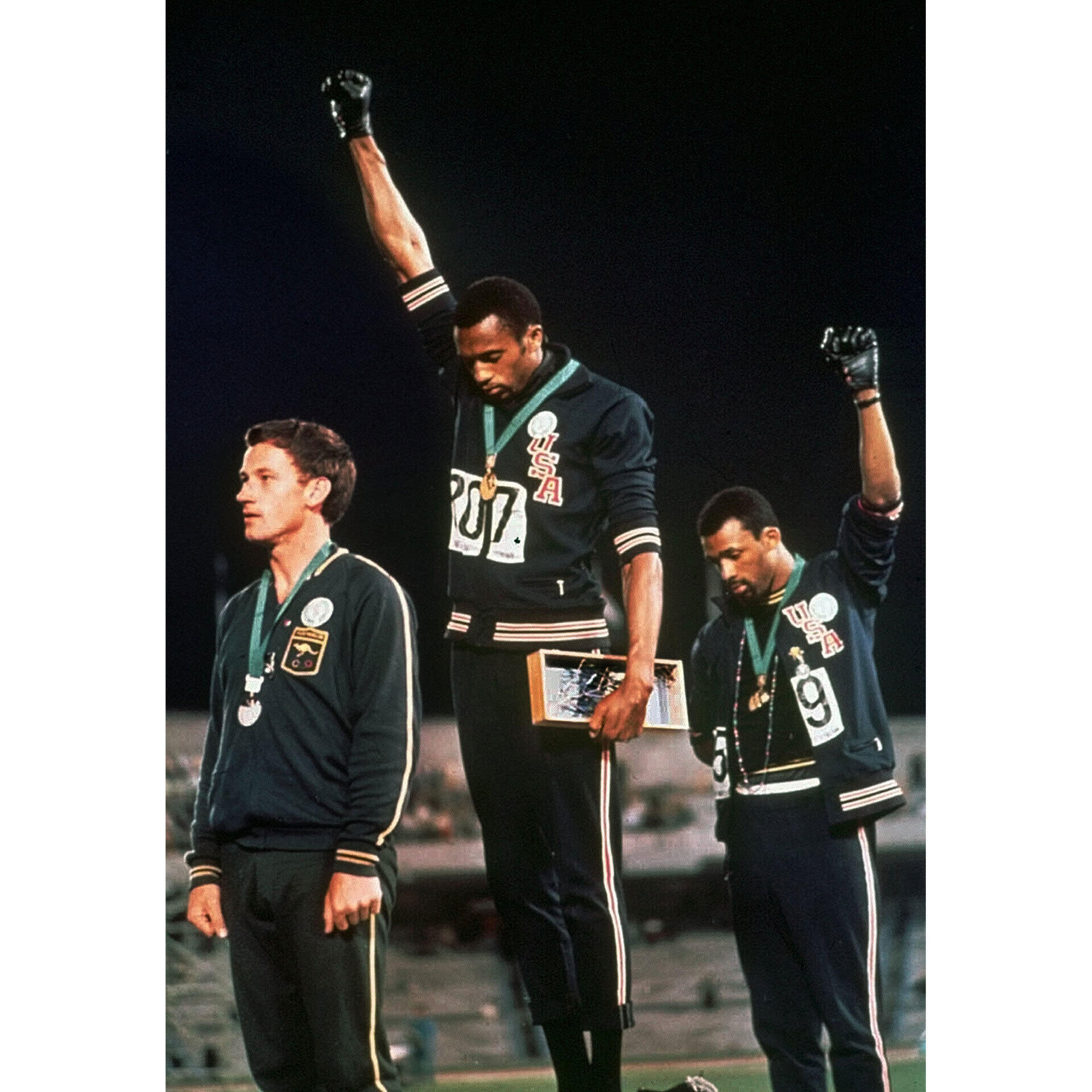 Tommie Smith (au centre), John Carlos (à droite) et Peter Norman (à gauche) sont sur le podium après la finale du 200 mètres aux Jeux de 1968 à Mexico.