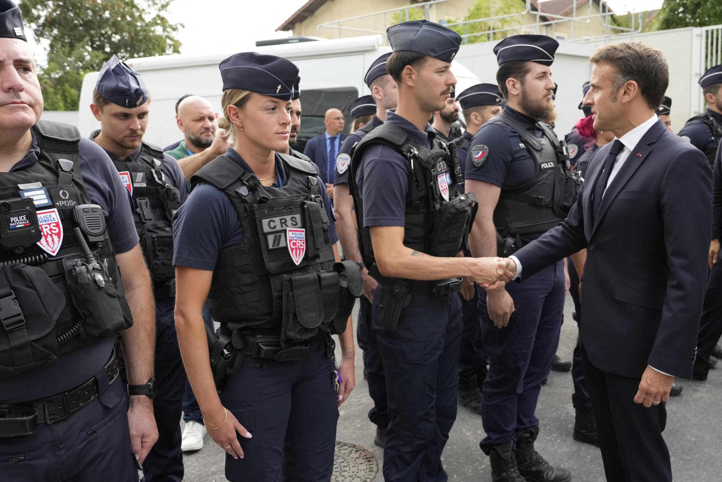 Le président français Emmanuel Macron (à droite) serre la main d'un policier anti-émeute alors qu'il visite le village olympique, à Saint-Denis, dans le nord de Paris, le 22 juillet 2024, avant la cérémonie d'ouverture des Jeux olympiques et paralympiques de Paris 2024.