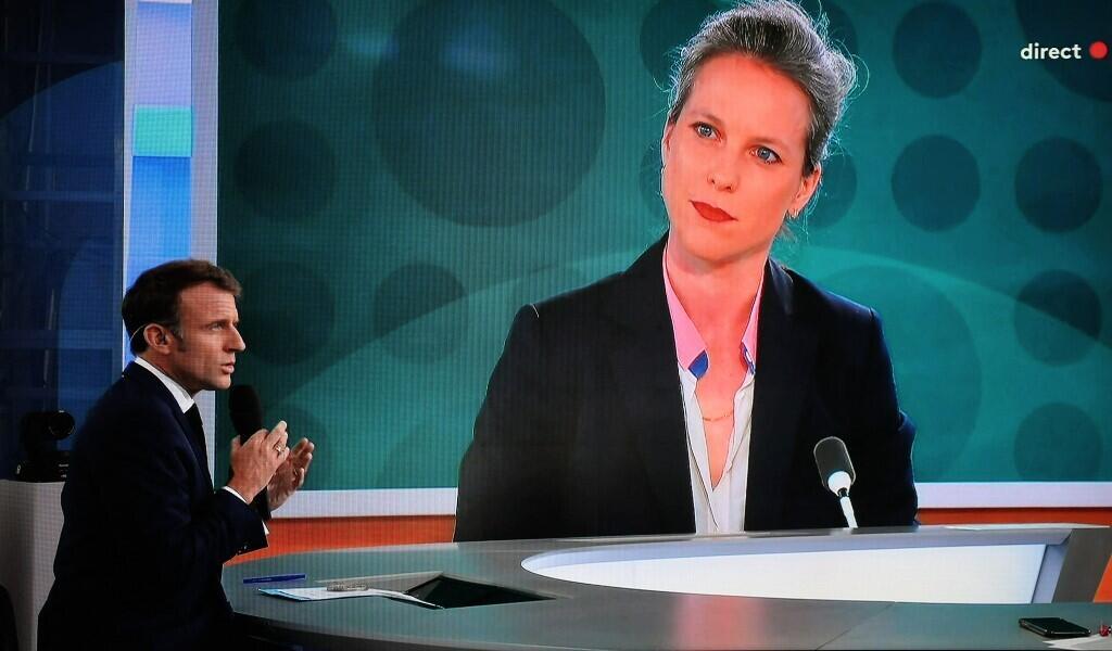 Cette photographie montre un écran de télévision diffusant le président français Emmanuel Macron s'adressant à une interview en direct alors qu'un portrait de Lucie Castets, le choix du « Nouveau Front populaire » pour le poste de Premier ministre, est affiché sur un écran géant, sur la chaîne de télévision française France 2, sur un plateau installé sur le toit du Musée de l'Homme au Trocadéro à Paris, le 23 juillet 2024.