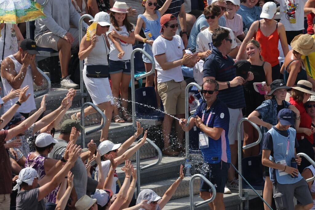 Un membre du personnel asperge les spectateurs d'eau pendant une pause lors d'un match de beach-volley au stade de la Tour Eiffel le 30 juillet.