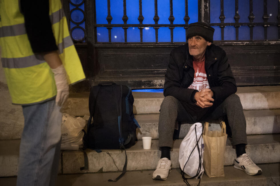 Une bénévole du Secours Populaire discute avec un SDF lors d'une distribution de nourriture et de vêtements à Paris.