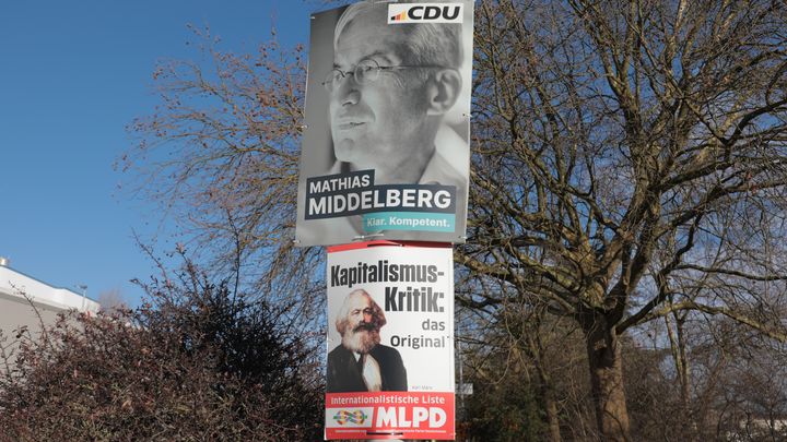 Des affiches du Parti marxiste-léniniste d'Allemagne et de l'Union chrétienne-démocrate d'Allemagne devant l'usine Volkswagen d'Osnabrück (Basse-Saxe), le 28 janvier 2025. (ZOE AUCAIGNE / FRANCEINFO)