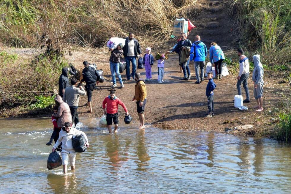 Les gens traversent la rivière Nahr al-Kabir, formant la frontière entre la province côtière ouest de la Syrie et le nord du Liban dans la région de Hekr al-Daher le 11 mars 2025, alors que les familles de la minorité alaouite de la Syrie entrent au Liban tout en fuyant la violence secrète dans leur cœur le long de la côte méditerranéenne du Syrie.
