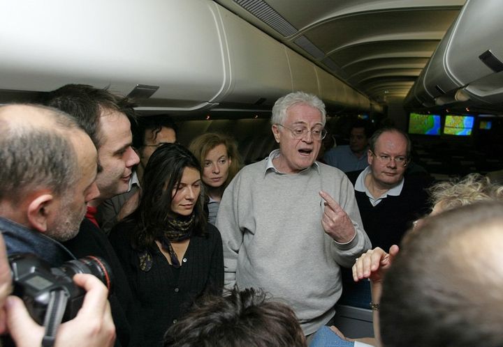 Lionel Jospin s'entretient avec des journalistes, sous le regard de son porte-parole Yves Colmou, le 9 mars 2002, dans l'avion qui les ramène à Paris, après sa visite d'une journée sur l'île de La Réunion. (PHILIPPE DESMAZES / AFP)